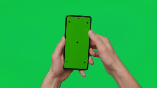 Male Hand Holding a Smartphone with Vertical Green Chroma Key Screen Isolated on Green Mobile Phone