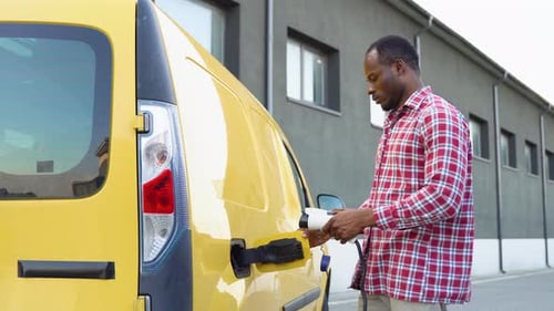 Black Man Charging Cargo Electric Car Near Warehouse Green Energy Eco Friendly Fuel