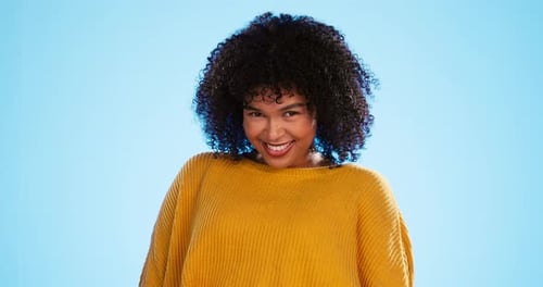 Face, funny and black woman with smile, excited and cheerful against a blue studio background