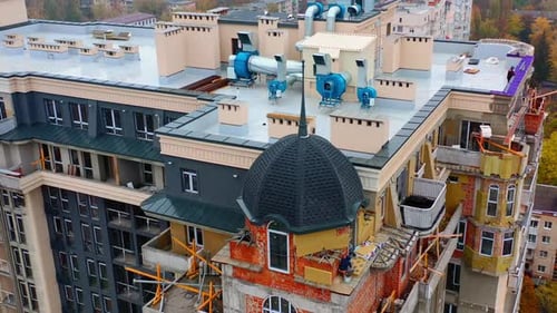 Construction of modern tower house. Workers build the on the top of multi-storey building.