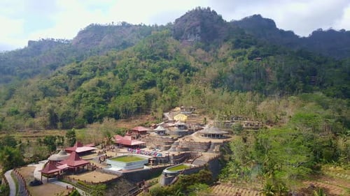 Vista aérea da atração turística “Watu Putih” com colinas ao fundo.