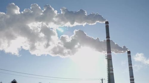 Industrial Smokestacks Emitting Smoke Against Bright Blue Sky