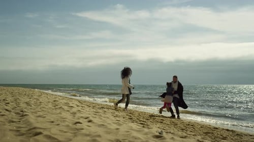 Cheerful family vacation at sea beach joyful parents and child spinning around