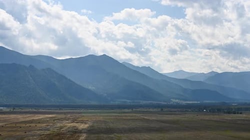 Cumulus clouds running over a valley and mountain landscape