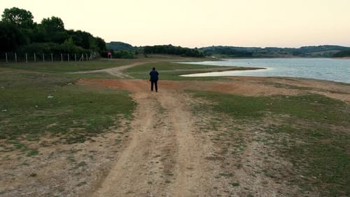 Adult Walks Path Near Lake at Sunset