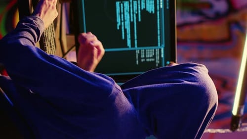 Adult with Hoodie Coding in Neon-Lit Urban Setting
