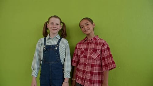 Two young girls in front of a green wall