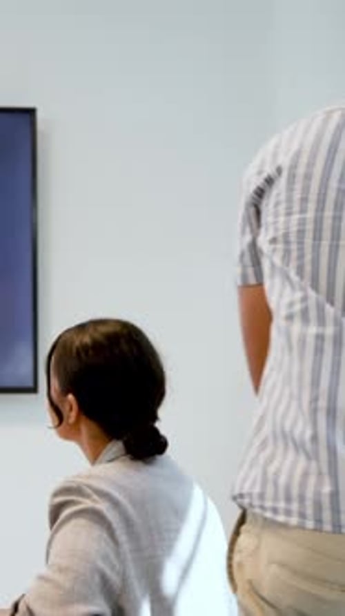Vertical video: Diverse coworkers in office leaning and discussing graph on display, copy space