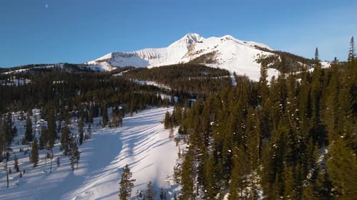 A drone shot of snowy Big Sky, Montana in winter, showcasing the ski resort and majestic mountain te