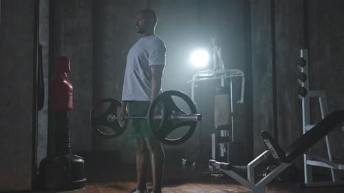 Man Performing Deadlifts in Dark Fitness Room