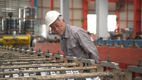 Senior experienced technician checking large machine on a production line at an industrial factory