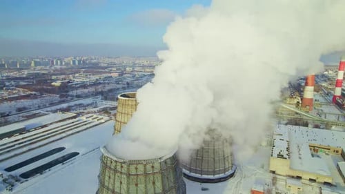 Winter View of Steam Rising From Cooling Towers at an Industrial Site in a Snowy City