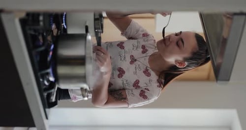 Young Woman Cooking and Tasting Food in Kitchen