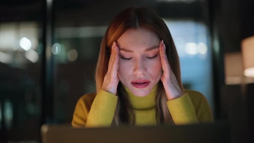 Woman Working at Night with a Headache