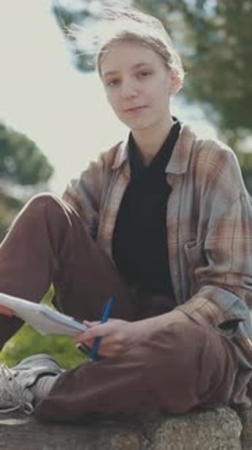 Young Woman Writing Outdoors in a Park