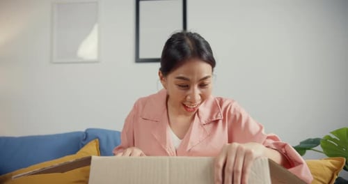 Young Woman Excitedly Opens a Cardboard Box