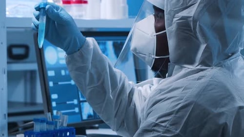 Scientist in Protective Suit Examining Test Tube in Lab