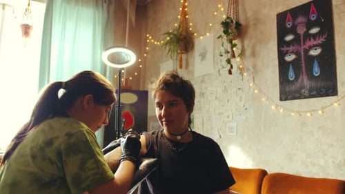 Tatuadora feminina trabalhando com o cliente em um estúdio doméstico