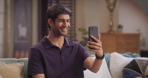 Young Man Smiling While Using Smartphone for Video Call