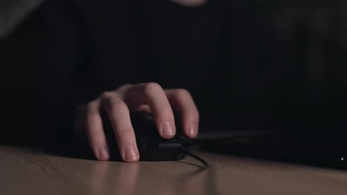 Gros plan des mains d'un joueur utilisant une souris d'ordinateur jouant à un jeu vidéo la nuit. Un hacker masculin fait une pause