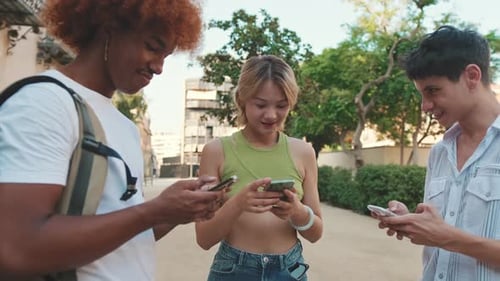 Close-up of joyful friends use smartphones outdoors, texting and scrolling through social networks