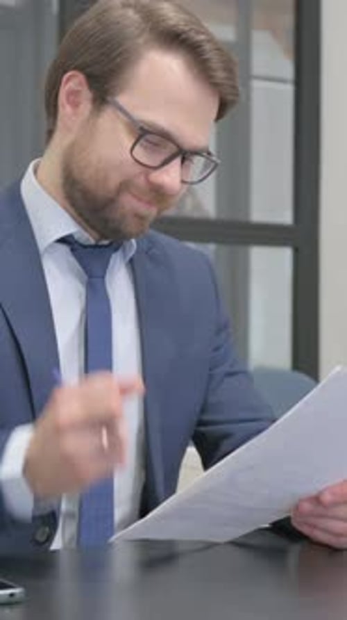 Man Reviews Documents at Desk in Office