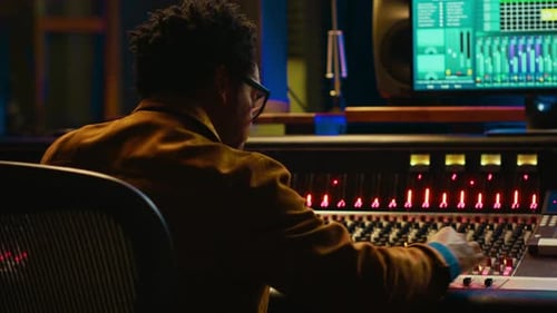 African American Audio Engineer Using Sound Mixing Console for Managing Tracks