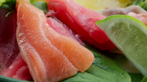 Close up of fresh raw fish slices with greens in a salad