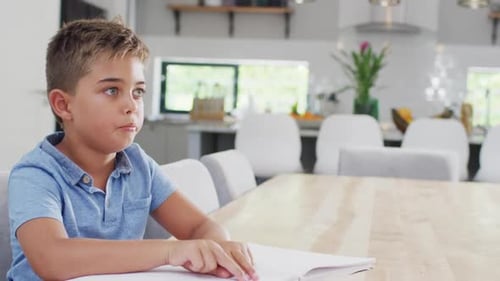 Kaukasischer Junge sitzt am Tisch und liest Braille, Zeitlupe