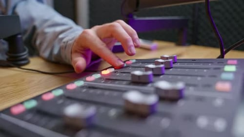 Close-up of hands adjusting knobs on a professional sound engineering console in a podcast or music.