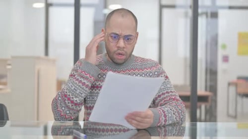 Man Reacts to Documents with Shock in Office