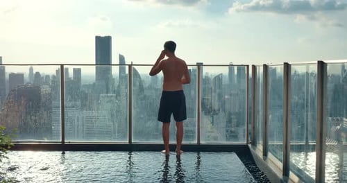 Man Stands on Rooftop with Pool in Nice Luxury Hotel Mesmerized By Cityscape Rooftop with Pool