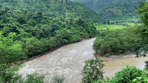 A flooding river in the shadow of the hills of Nepal.