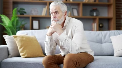 Senior Man Sitting Thoughtfully on Sofa Indoors