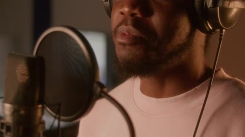 Nahaufnahme eines Mannes, der während der Aufnahmesession in ein professionelles Mikrofon singt