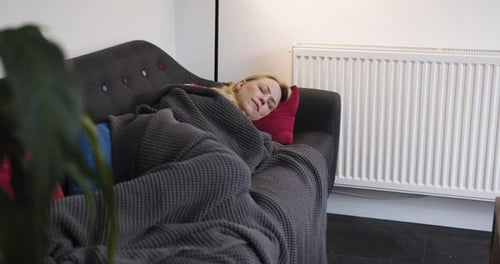 Woman Resting on Sofa Covered with Blanket