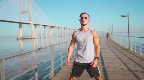 Athletic Man Stretching on Boardwalk Near Bridge