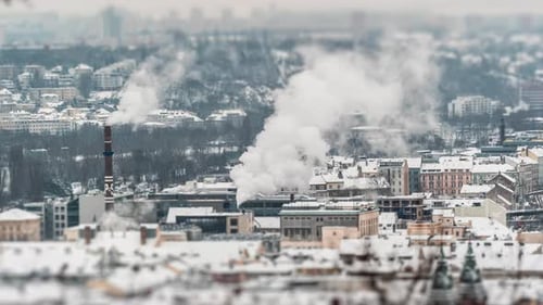 Prague urban landscape. Snow-covered roofs, smoke coming out of the high industrial chimneys. Smog h