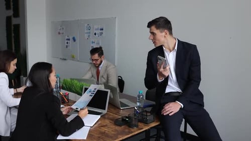 Group of Young Business People Working and Chatting While Sitting at the Office Table Together with