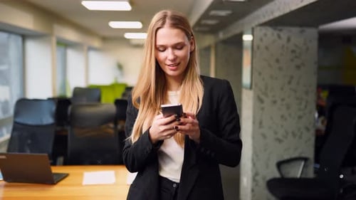 Smiling Business Woman Using Mobile Phone Typing Text Messages Standing in Office Portrait of Female