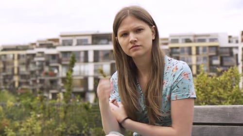 A Beautiful Young Caucasian Woman Acts Anxious As She Sits on a Bench in an Urban Area
