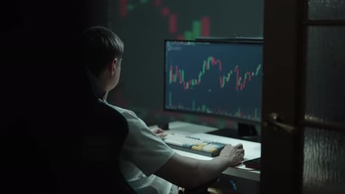Tracking Shot of Young Financial Trader Analyzing Real Time Stock Market Data on Computer Screen