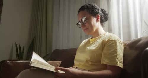 Young Woman Reading Book in Cozy Living Room Turning Page Learning Studying Education Read Books