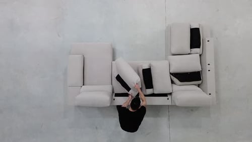 Man Arranges Cushions on a Modular Sofa