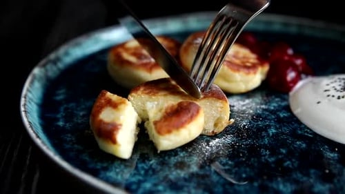 Cutting Into Delicious Syrniki Breakfast on a Decorative Plate