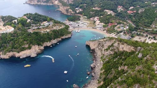 Aerial View of Paleokastritsa Bay in Corfu Greece Featuring Turquoise Waters Boats and Rugged Green