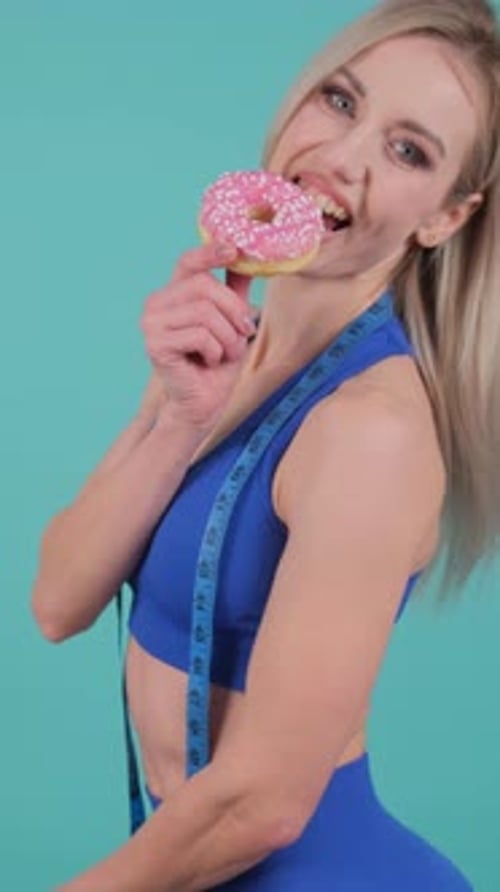 A Woman Humorously Juggles Indulgence with Selfcontrol Biting a Donut