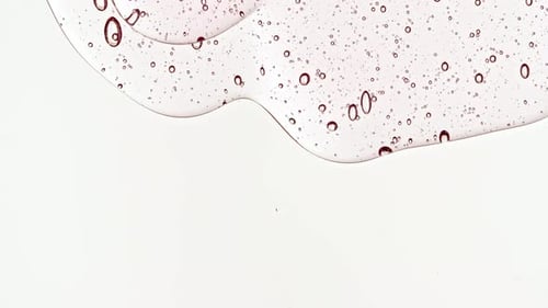 Transparent Cosmetic Gel Fluid With Molecule Bubbles Flowing On The Plain White Surface Macro Shot