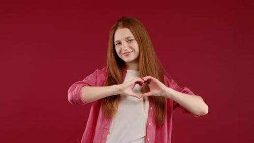 Smiling Woman Makes Heart Shape with Hands