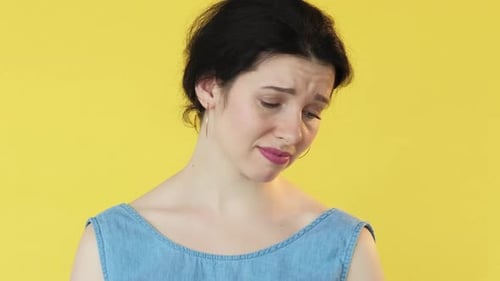 Woman Expressing Sadness in Close-Up on Yellow